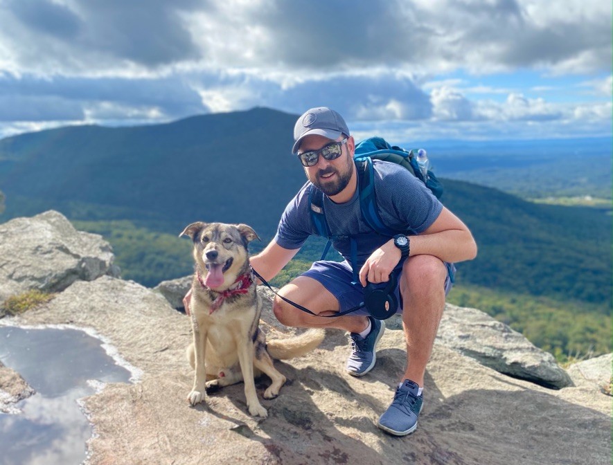 Ascendient Managing Consultant Jon Rodgers on a mountaintop with his dog, Oliver