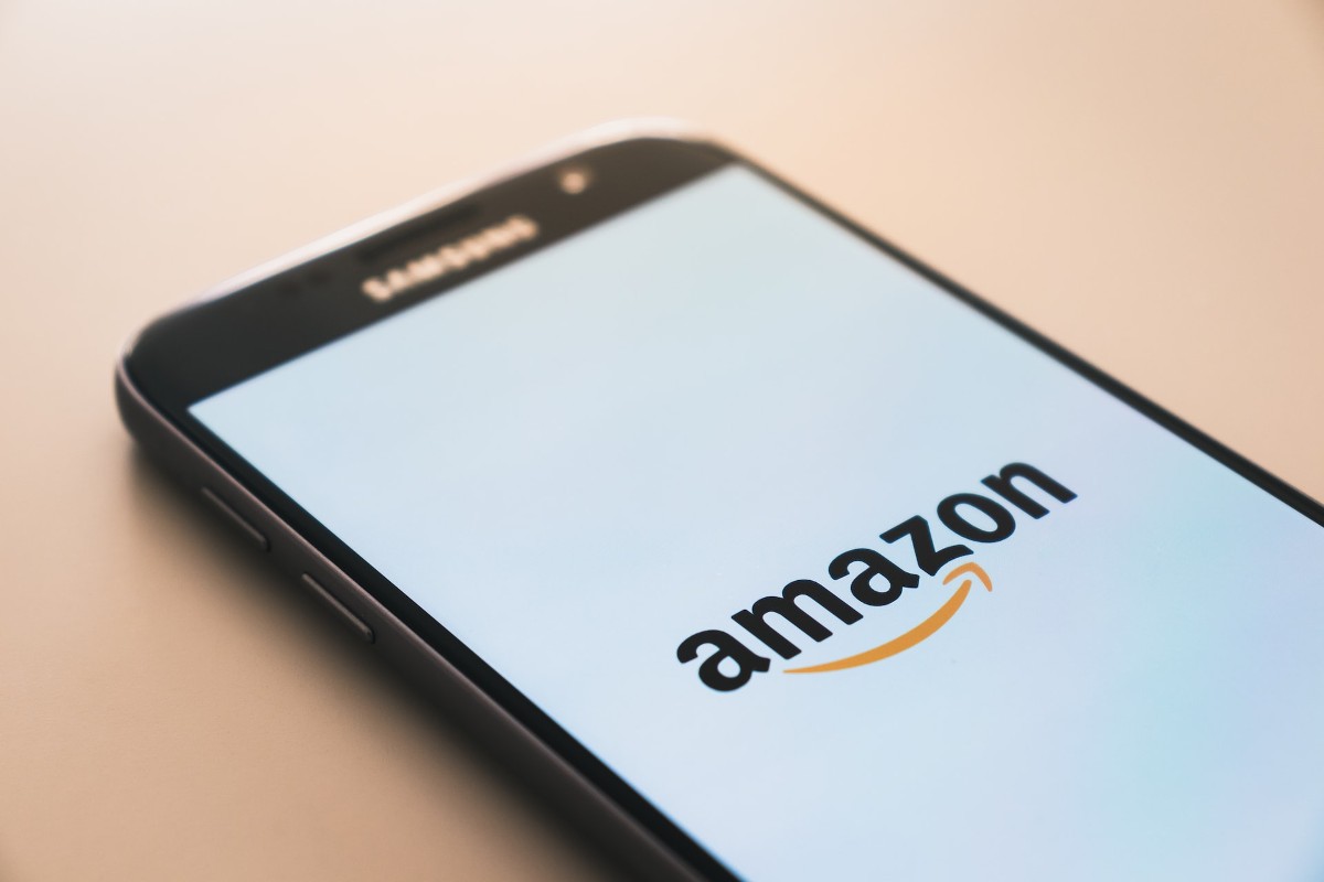 A mobile phone displays the Amazon logo on its home screen