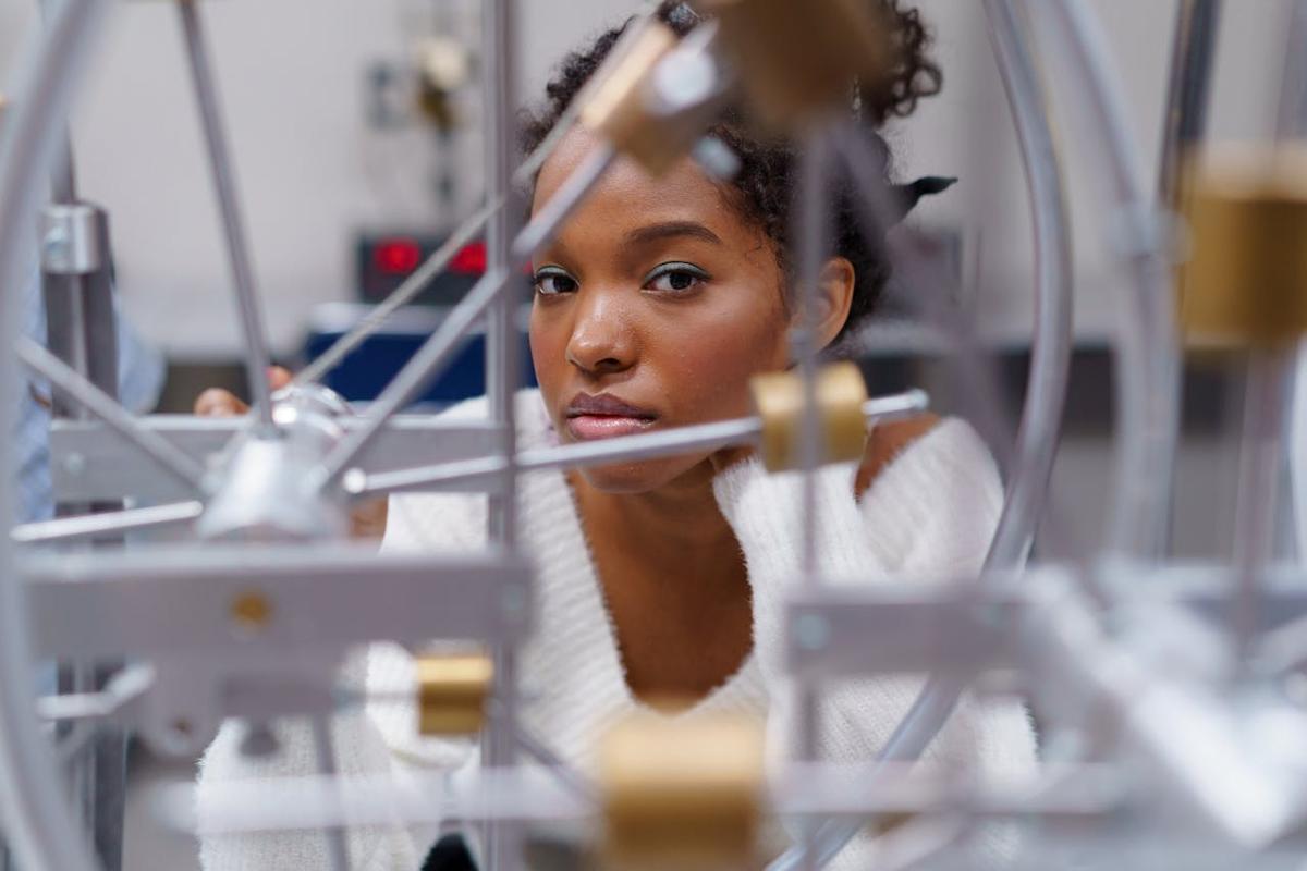 A high school science student looks at the camera through a piece of scientific equipment