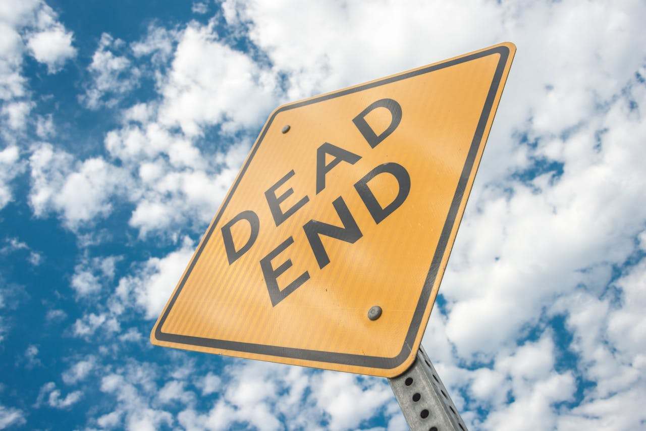A DEAD END sign stands against a partly cloudy sky, suggesting the end might be near for private equity investments in physician groups.